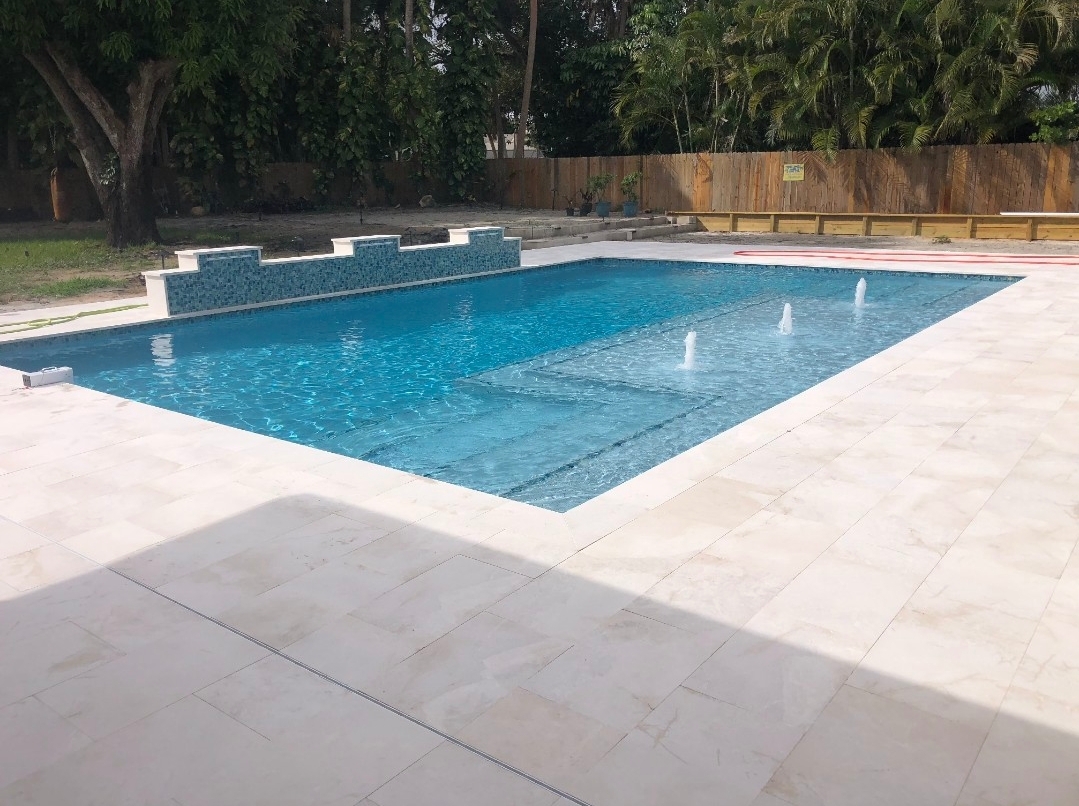New in-ground pool with a light paver deck and water jets